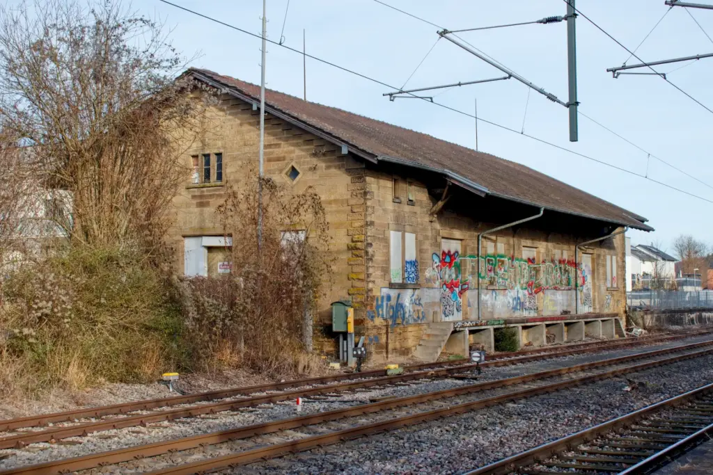 Lagerschuppen an drei Bahngleisen. Der Schuppen hat viele Grafittis und wirkt alt und verwahrlost